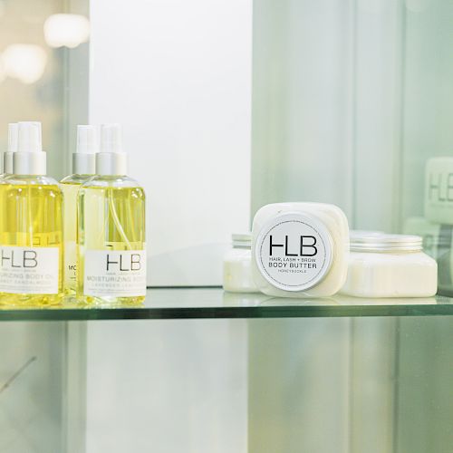 The image shows a glass shelf with HLB Rejuvenist products, including spray bottles and cream jars, neatly arranged on it.