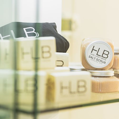 The image features HLB-labeled products, including soap bars and jars of salt scrub, displayed on a glass shelf.