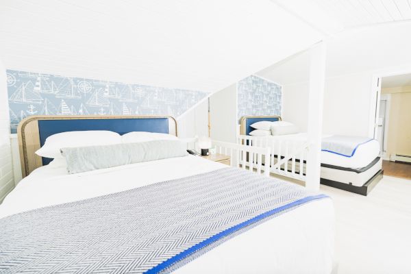 A bright, nautical-themed bedroom with two beds, maritime wallpaper, and a light color scheme ending the sentence.
