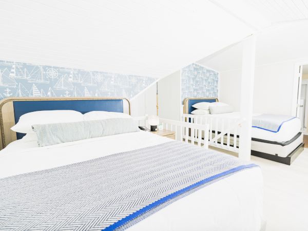 A bright, nautical-themed bedroom with two beds, maritime wallpaper, and a light color scheme ending the sentence.