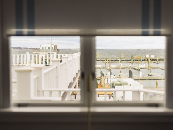 View through a window featuring a marina with docks extending into a bay, under a cloudy sky.