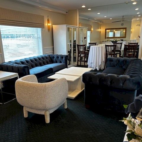 A modern conference room with a long table, white chairs, and a presentation screen at the front.