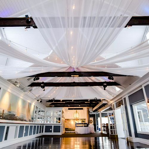 The image features a beautifully decorated event venue with draped white fabric on the ceiling and warm lighting, creating an elegant atmosphere.