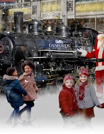 Children in winter clothing are near Santa Claus, standing in front of a steam locomotive in a festive setting.