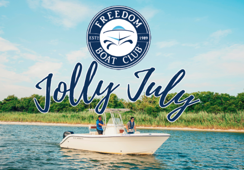 A boat on the water with two people onboard, featuring the "Freedom Boat Club" logo and the text "Jolly July" against a scenic backdrop.