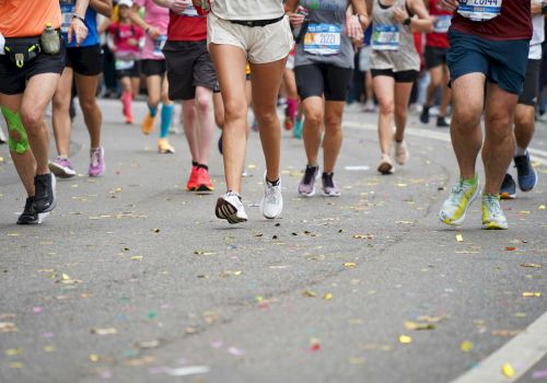 A group of runners participating in a marathon or race on a road, wearing various athletic attire and running shoes.