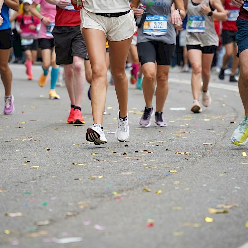 A group of runners participating in a marathon or race on a road, wearing various athletic attire and running shoes.
