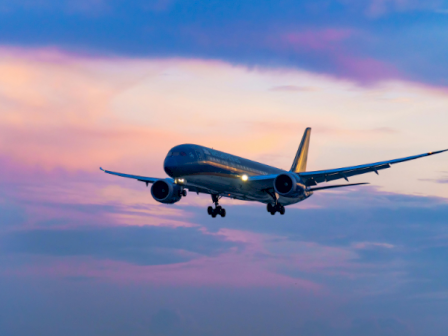 A passenger jet climbs through a colorful sunset sky, wings spread, preparing for landing or takeoff.