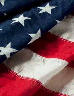 Close-up of a waving American flag, showing blue field with white stars and red-and-white stripes.